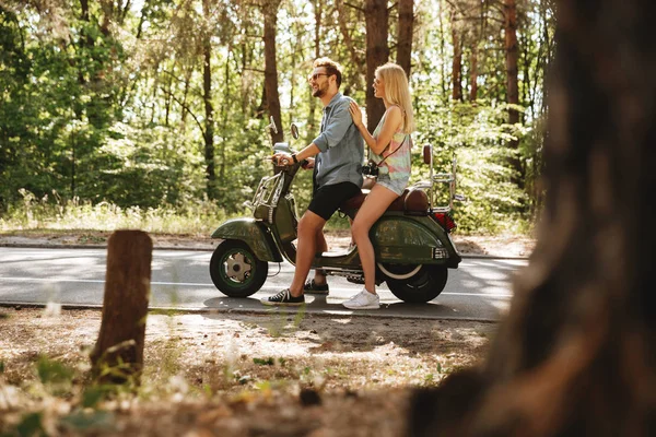 Bearded man on scooter with happy girlfriend outdoors