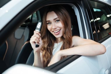 Yeni arabası içinde oturan mutlu gülümseyen kadın