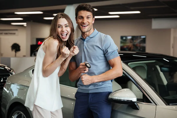 Couple aimant debout près de la voiture dans le concessionnaire automobile . — Photo
