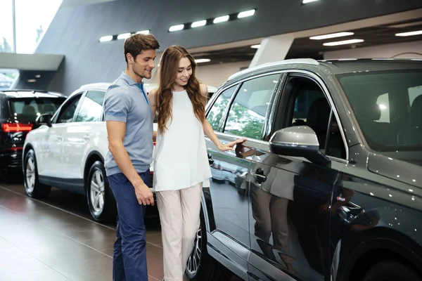 Hermosa pareja joven de pie en el concesionario de automóviles —  Fotos de Stock