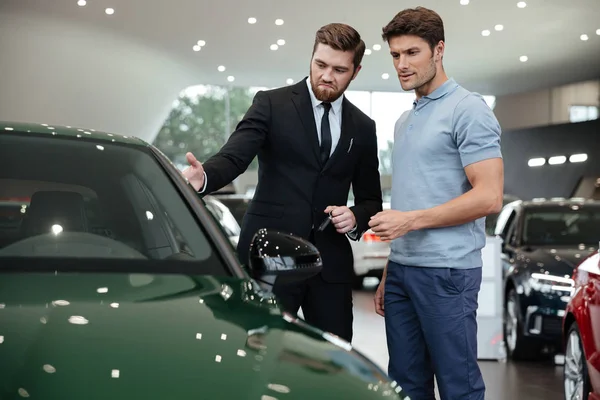 Stilig ung bilförsäljare visar en ny bil — Stockfoto