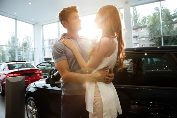 Feliz joven pareja abrazándose después de comprar un coche nuevo —  Fotos de Stock