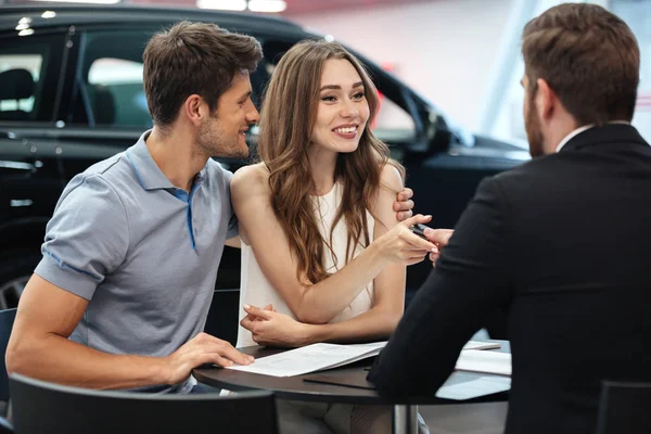 Confiado joven vendedor explicando todas las nuevas características del coche —  Fotos de Stock