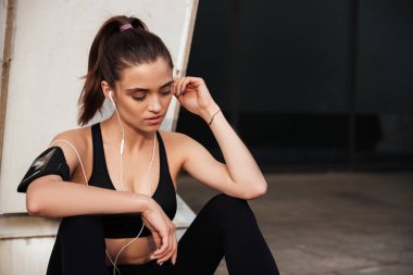 Earphones ile oturan genç spor Bayan konsantre