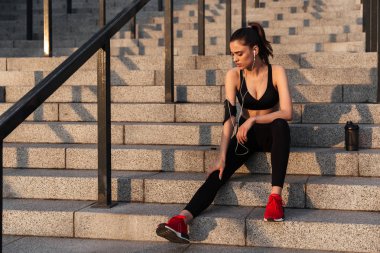 Earphones ile oturan ciddi genç spor Bayan