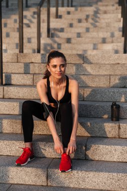 Earphones ile oturan ciddi genç spor Bayan