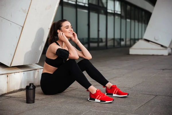 Hermosa joven deportista sentada con auriculares —  Fotos de Stock