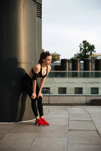 Señorita deportiva concentrada de pie con auriculares —  Fotos de Stock