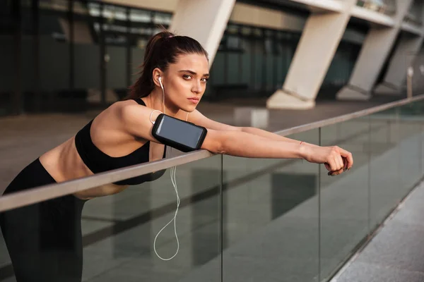 Hermosa joven mujer de los deportes de pie con auriculares —  Fotos de Stock