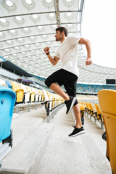 Vista lateral de um atleta esportivo correndo lá em cima — Fotografia de Stock