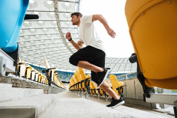 Vista lateral de un joven corredor masculino corriendo arriba — Foto de Stock