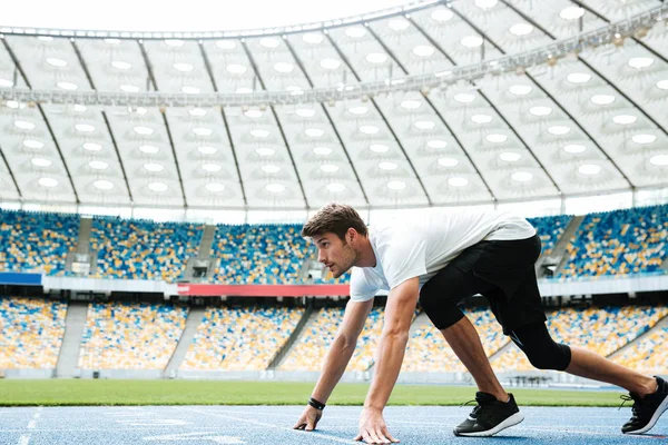 Zijaanzicht van een jonge atleet op de uitgangspositie — Stockfoto