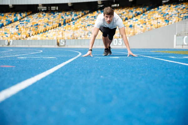 Jonge mannelijke atleet die permanent in een beginpositie — Stockfoto