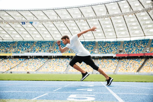 Bir koşu parkurundakilerden koşan bir spor adam yan görünüm