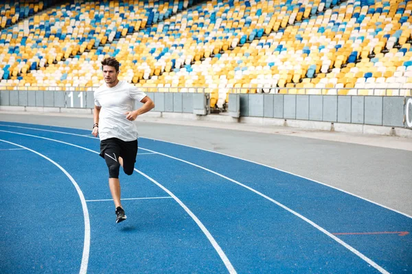 Jovem velocista correndo na pista de atletismo — Fotografia de Stock