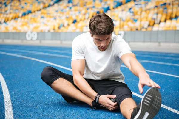 Jovem desportista do estádio faz exercícios de alongamento . — Fotografia de Stock