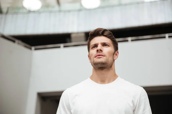 Joven deportista de pie cerca de la pared gris al aire libre — Foto de Stock