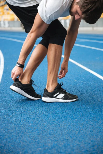 Atleta di sesso maschile in abbigliamento sportivo riscaldamento prima di correre — Foto Stock