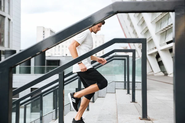 Side view of a young male runner running upstairs — Stock Photo, Image