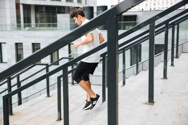 Vista lateral de un atleta deportivo corriendo escaleras abajo —  Fotos de Stock