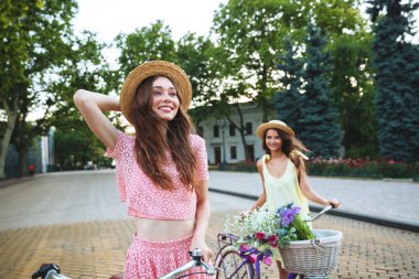 İki genç mutlu Bayan açık havada bisiklet ile ayakta