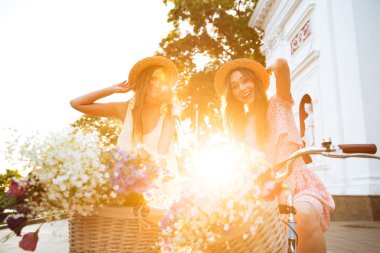 Genç bayanlar açık havada bisiklet üzerinde gülümseyen. Görünümlü kamera.