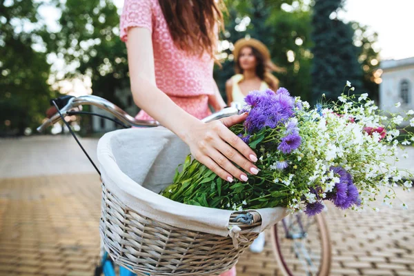 Two young ladies standing outdoors with bicycles. — Stock Photo, Image