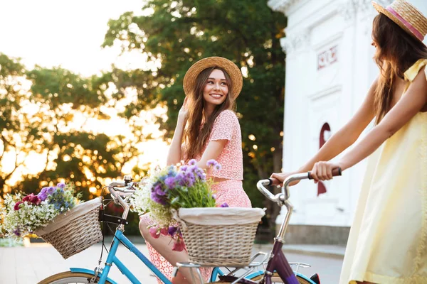 Duas mulheres sorridentes felizes em chapéus andando de bicicleta vintage — Fotografia de Stock