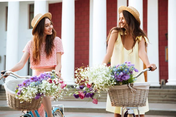 Duas jovens mulheres bonitas em vestidos sentados em bicicletas retro — Fotografia de Stock
