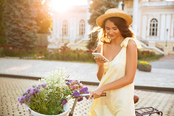 Cep telefonu kullaranarak elbise ve şapka gülümseyen güzel kız