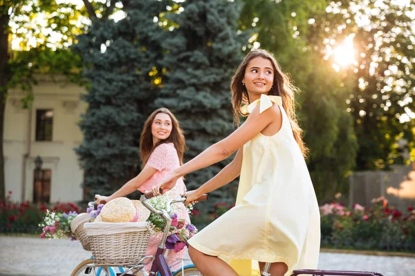 Two pretty young women riding retro bicycles — Stock Photo, Image