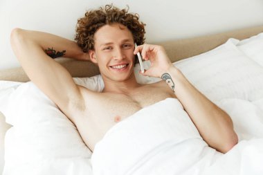 Cep telefonu üzerinde konuşurken kıvırcık saçlı mutlu gülümseyen adam