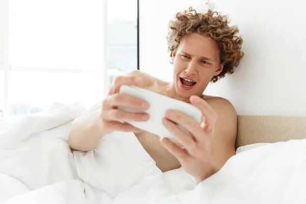 Young excited man playing games on mobile phone — Stock Photo, Image