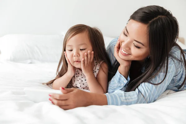 Junge Frau mit kleiner Tochter benutzt Handy. — Stockfoto