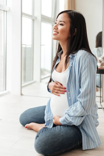 Joyeux jeune femme enceinte assis à la maison — Photo