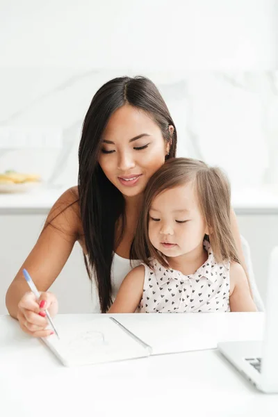 Mutter mit wenig süß asiatisch mädchen using laptop writing notes — Stockfoto