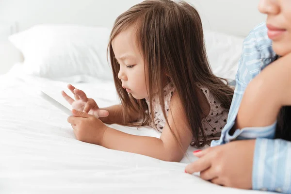 Küçük bebek kız yatakta yatan Smartphone ile oynamak — Stok fotoğraf
