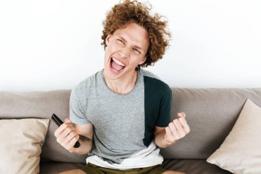 Mutlu bir adam tutarak uzaktan kumanda kazanan jest yapmak