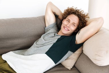 Yakışıklı gülümseyen adam kanepede yatıyor