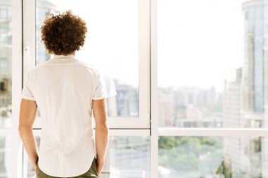 Yakışıklı adam kapalı pencere ayakta.