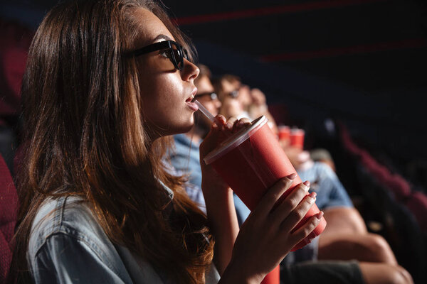 Lady sitting in cinema watch film drinking aerated sweet water.