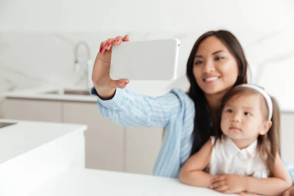 Glückliche junge Frau mit kleiner Tochter macht Selfie — Stockfoto