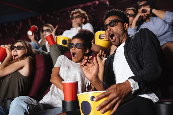 Jovens amigos assustados sentados no cinema assistir filme — Fotografia de Stock