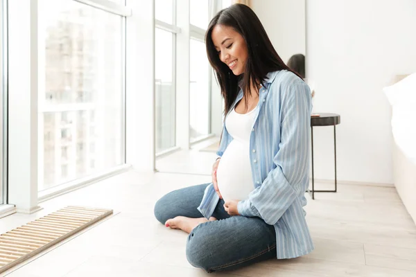 Feliz joven embarazada sentada en casa — Foto de Stock
