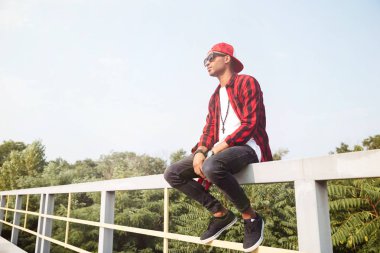 Çekici koyu tenli genç çocuk doğa backgro karşı oturan