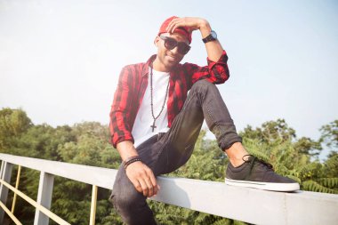 Neşeli koyu tenli adam doğa arka planı oturan