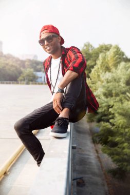 Neşeli koyu tenli adam geri doğaya karşı güneş gözlüğü takıyor