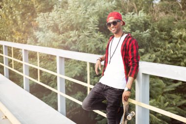 Neşeli koyu tenli adam kaykay holding