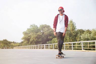 Güneş gözlüğü ve kaykay kap giyen adam koyu tenli