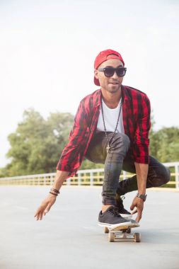 Genç koyu tenli adam kaykay